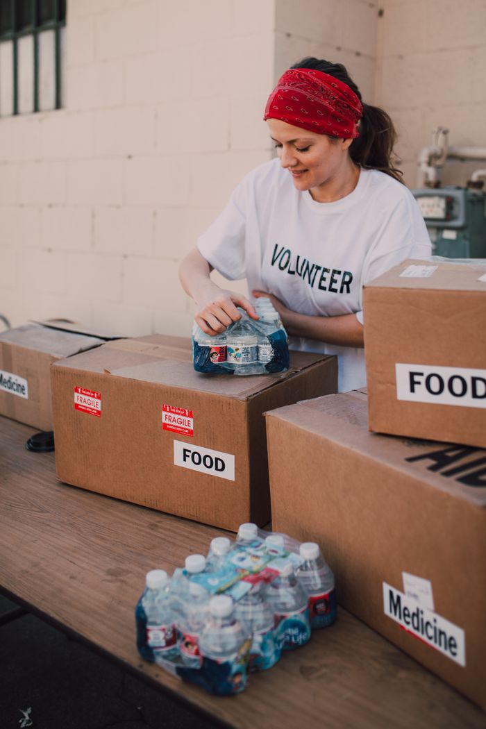 A volunteer packs food and water for a charity event outdoors, highlighting community support.